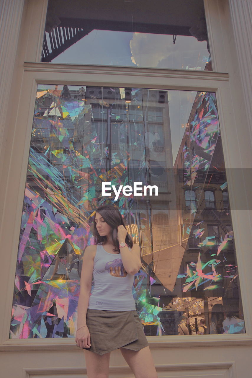 Woman standing by patterned window in city