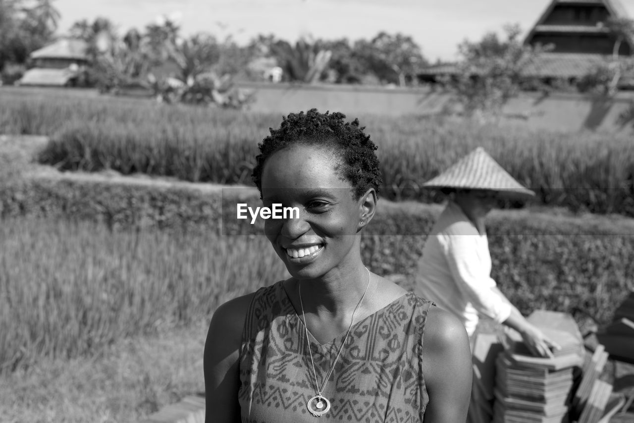 PORTRAIT OF SMILING YOUNG WOMAN IN FIELD