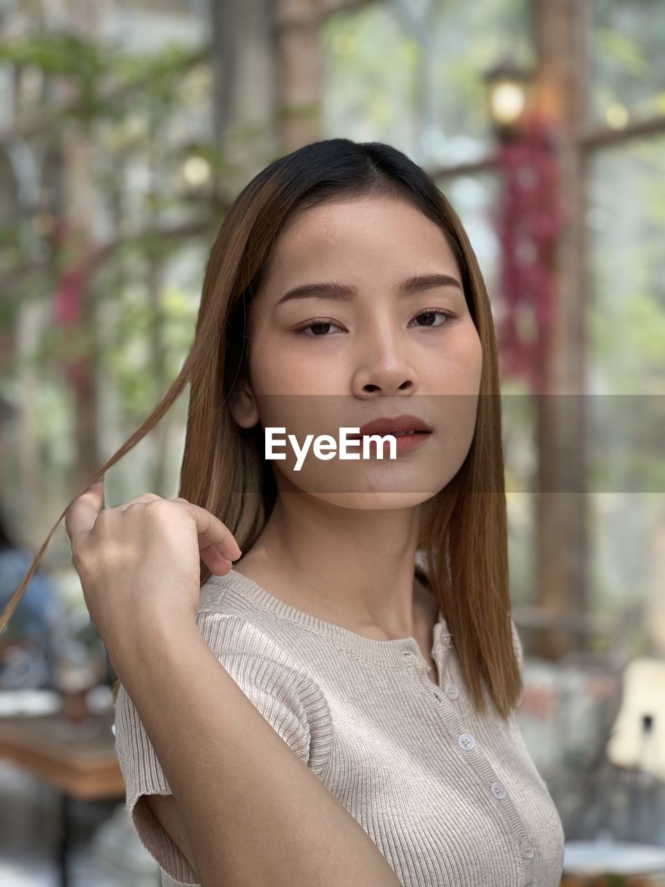 Portrait of young woman ,lao girl, playing with her hair in a bright restaurant