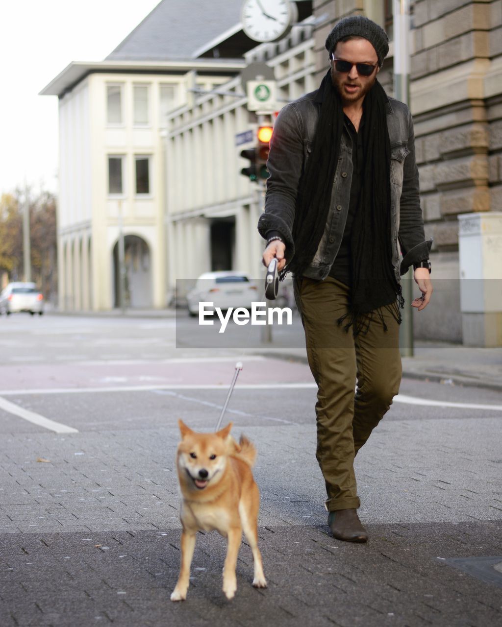 Portrait of man walking with shiba inu on footpath in city