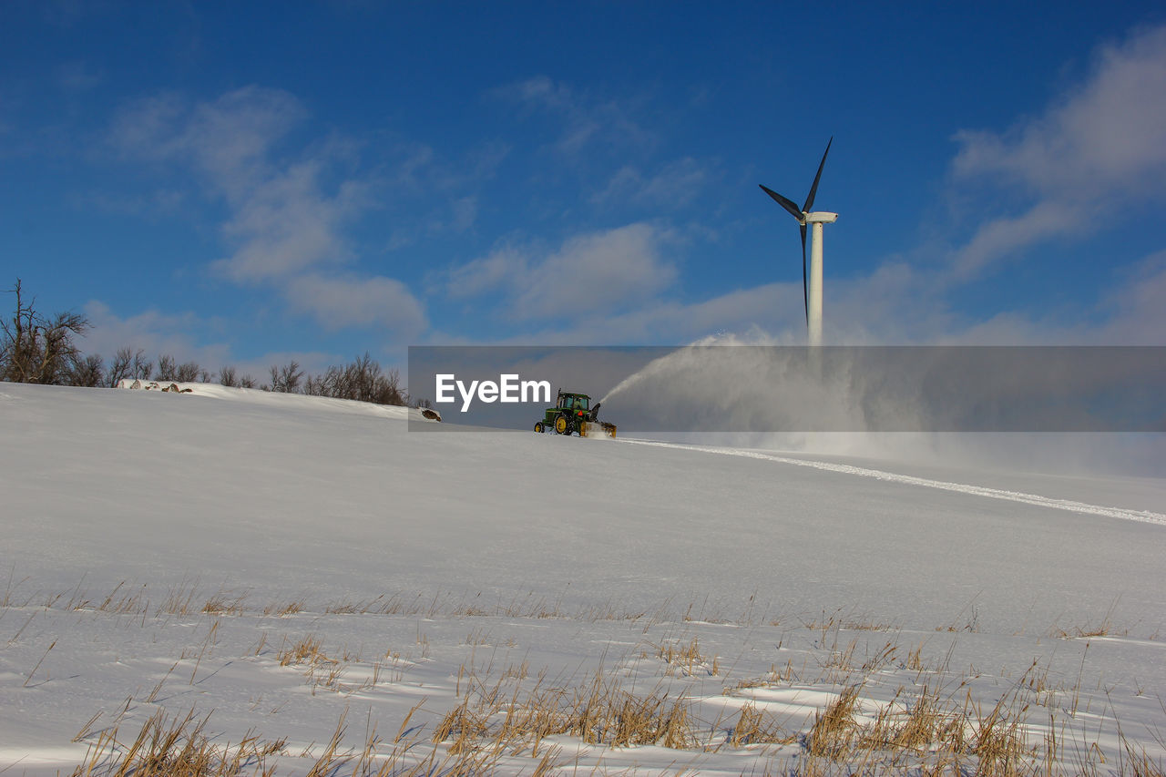 Windmills on snow field against sky