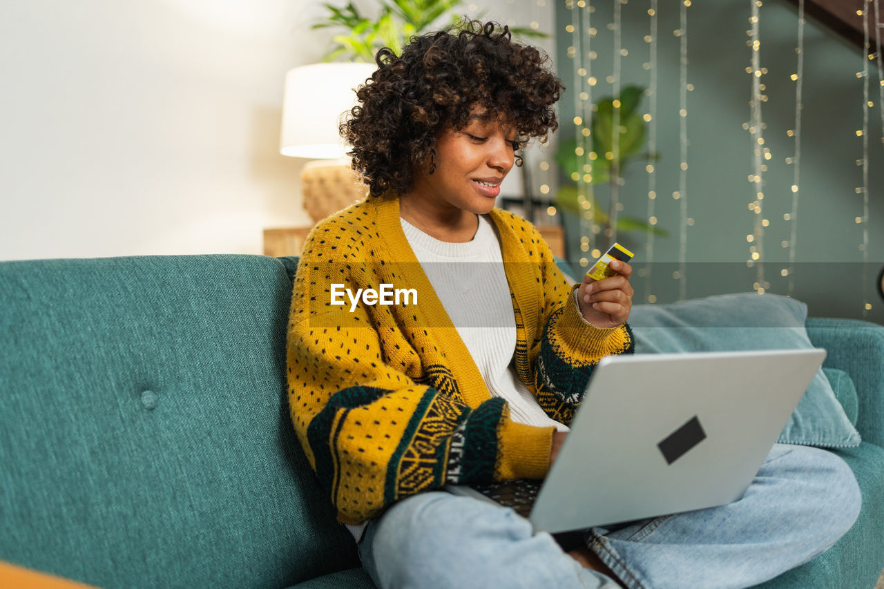 woman using laptop while sitting on sofa at home