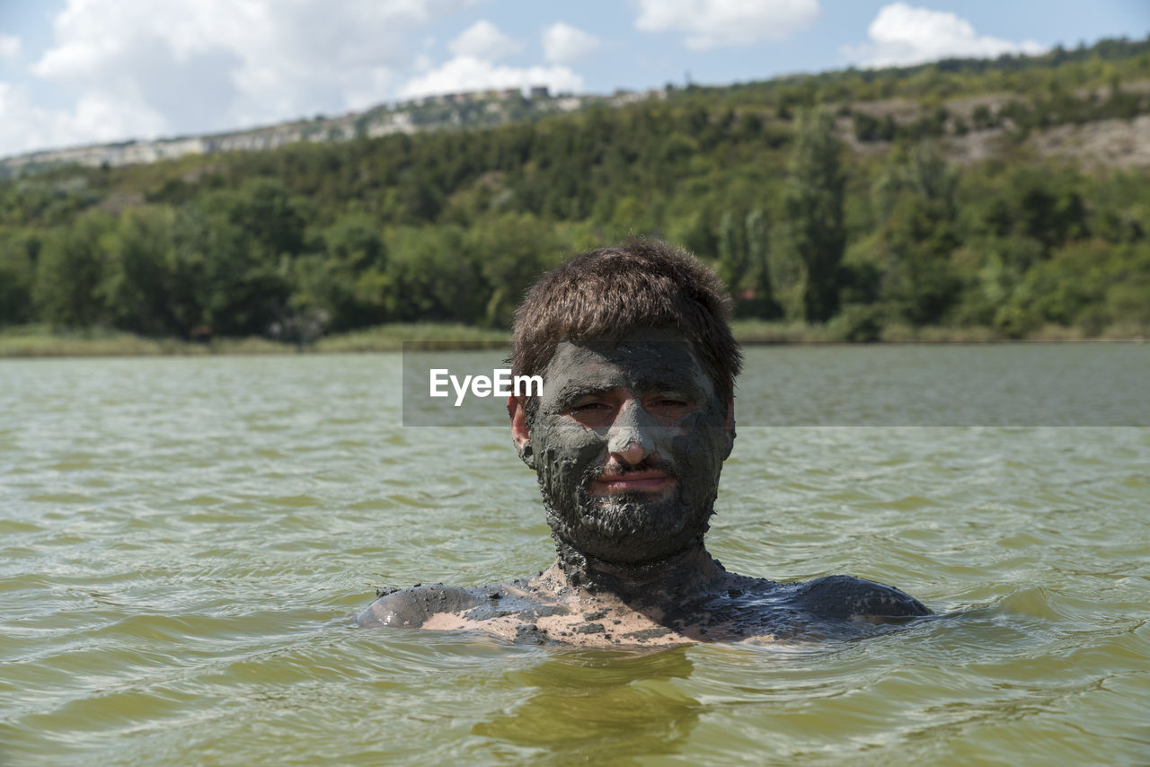 Portrait of man with mud on face in lake