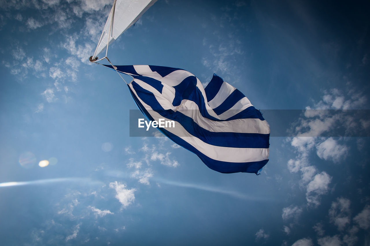 Low angle view of greek flag fluttering against blue sky