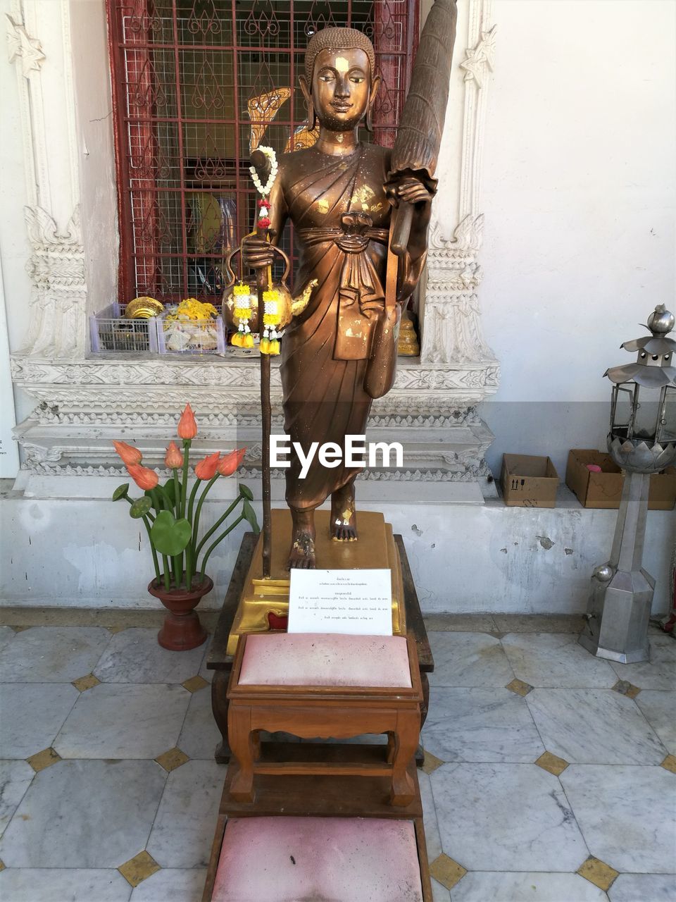 STATUE BY POTTED PLANTS OUTSIDE BUILDING