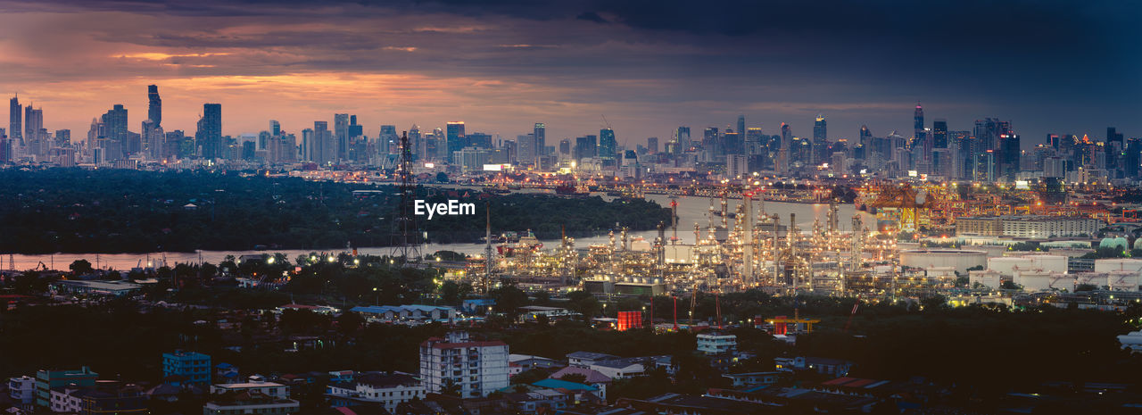 Panoramic view of illuminated buildings in city against sky at sunset