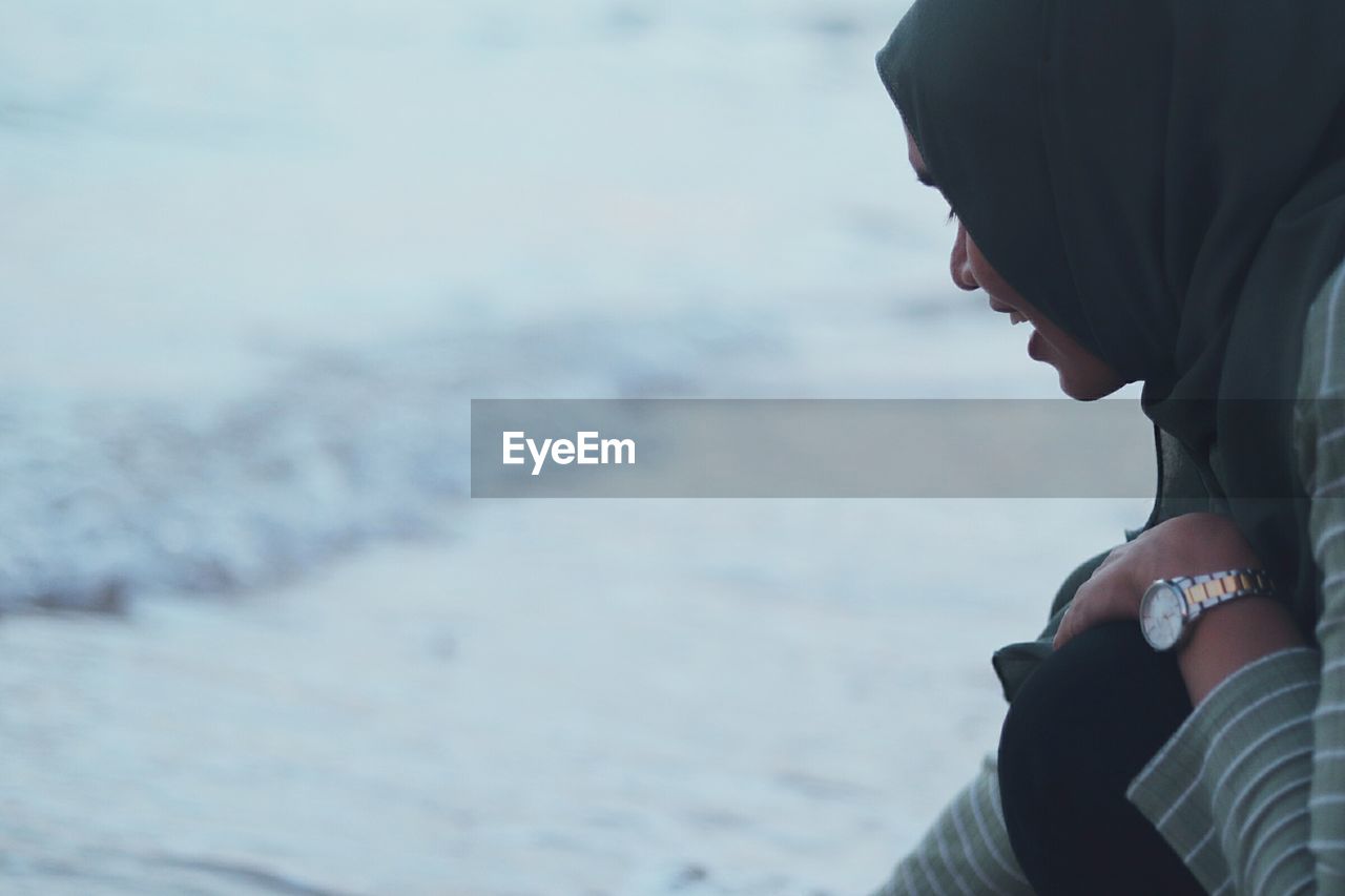 Side view of young woman wearing hijab on shore at beach