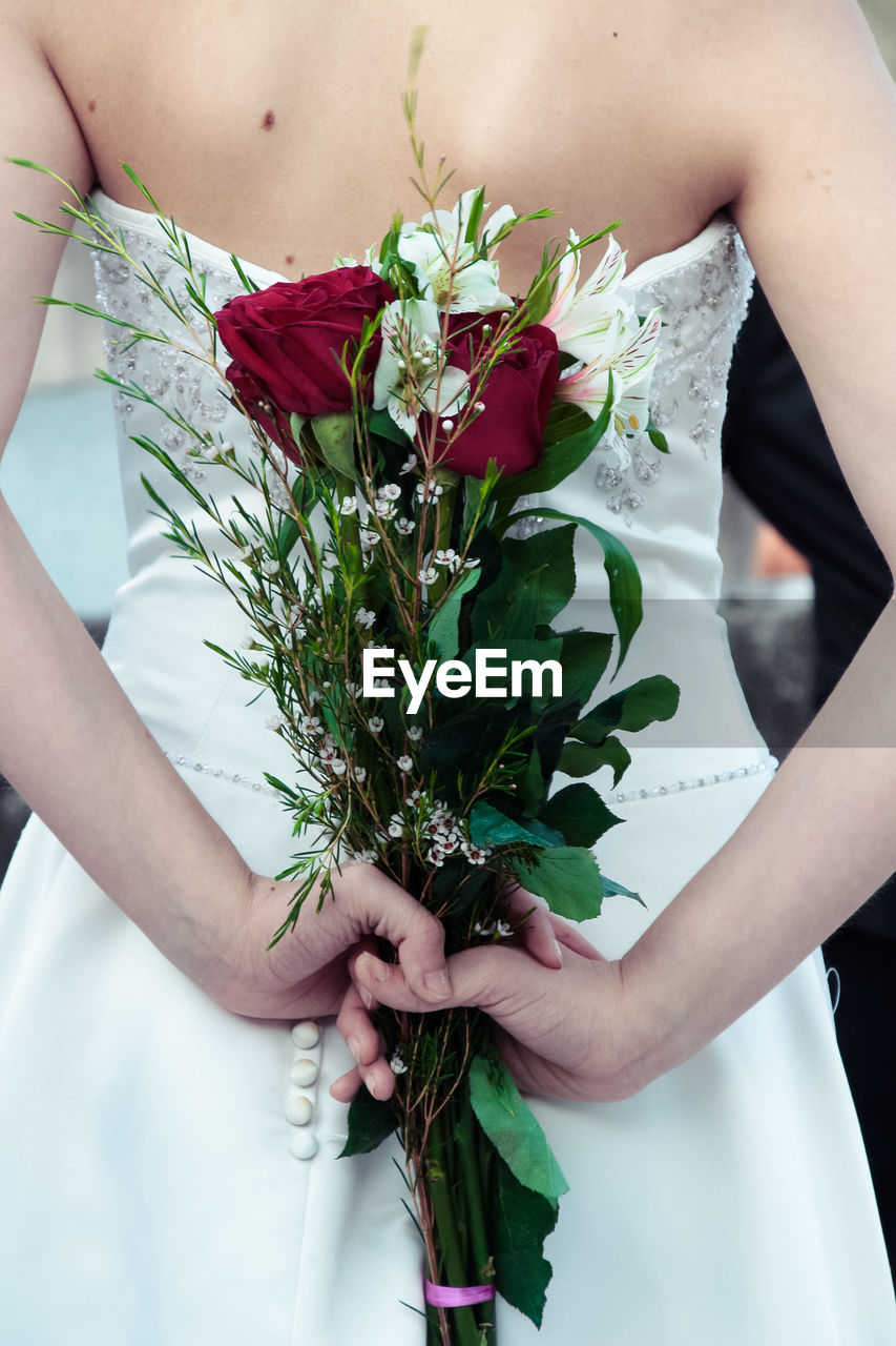 Midsection of bride holding rose bouquet