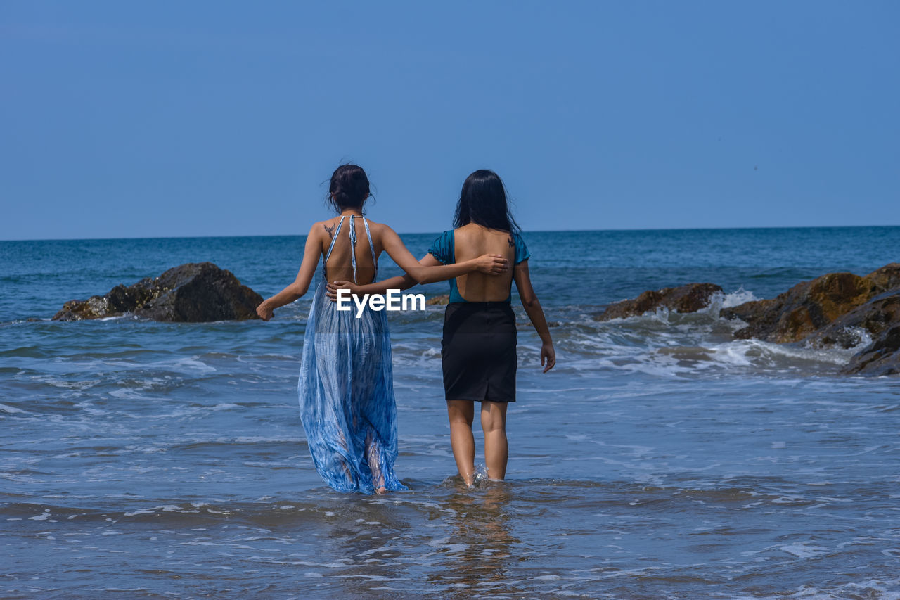 Rear view of woman standing in sea against clear sky