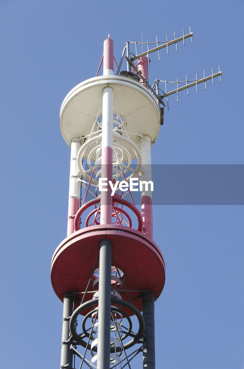 Low angle view of communications tower against clear blue sky