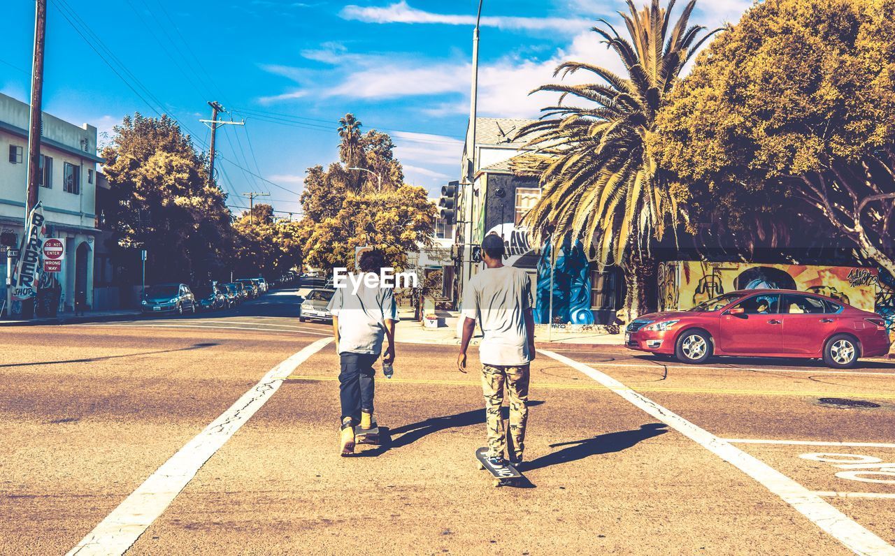 PEOPLE WALKING ON ROAD AGAINST TREES IN CITY