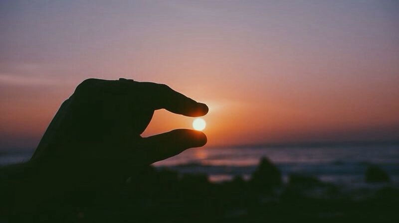 CROPPED IMAGE OF PERSON HOLDING SUN