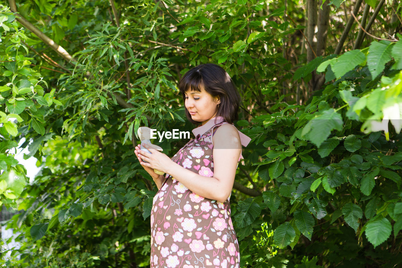 WOMAN STANDING BY PLANTS