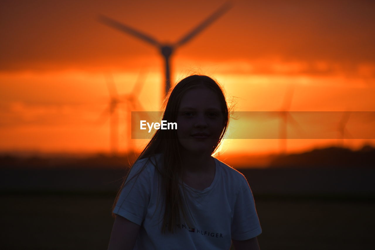 Girl and sunset over the holderness fields at rimswell east yorkshire uk wind turbine in background