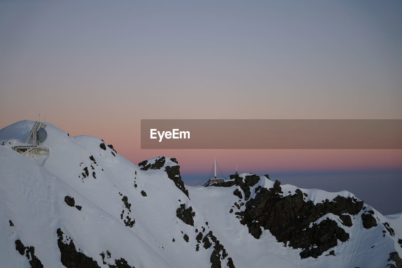PANORAMIC VIEW OF SNOWCAPPED MOUNTAINS AGAINST CLEAR SKY DURING SUNSET