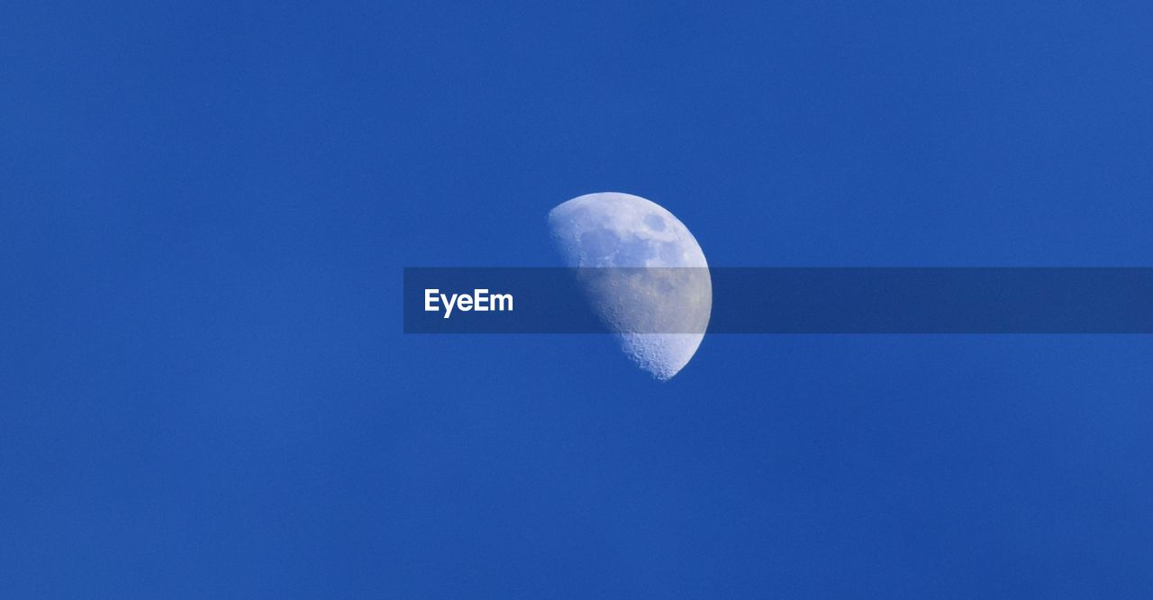 Low angle view of moon against clear blue sky