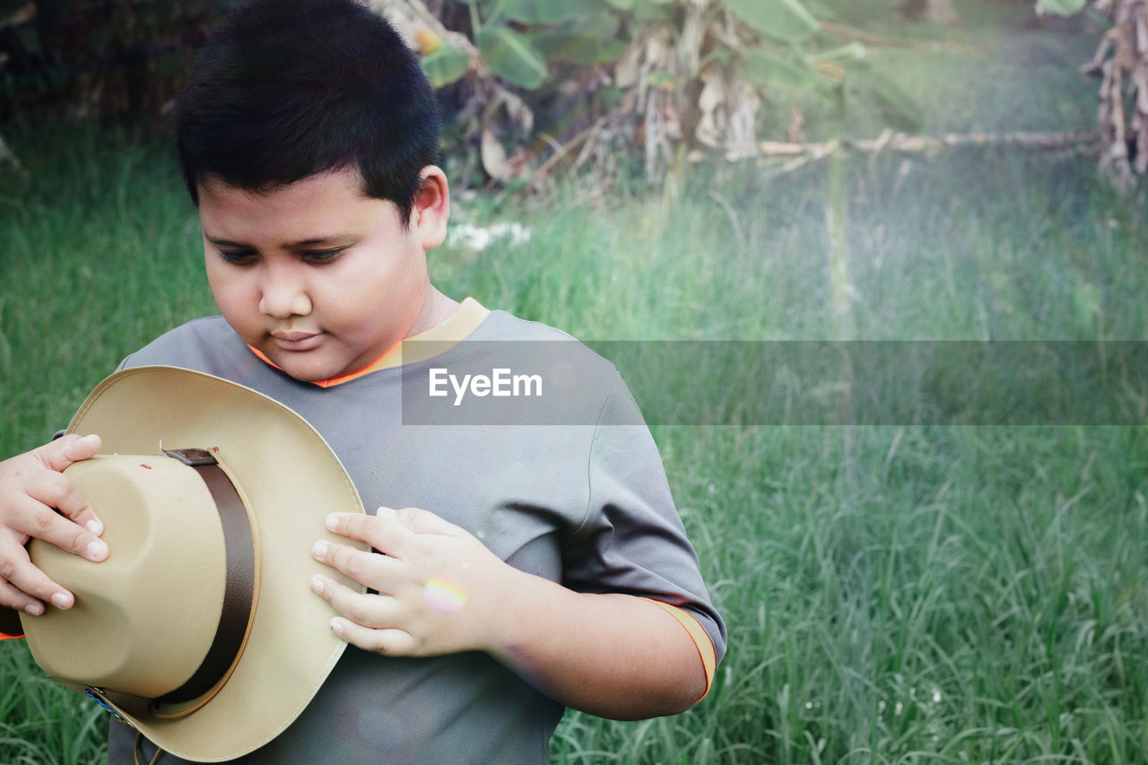 The boy with a hat behind his is a tree with soft sunlight.