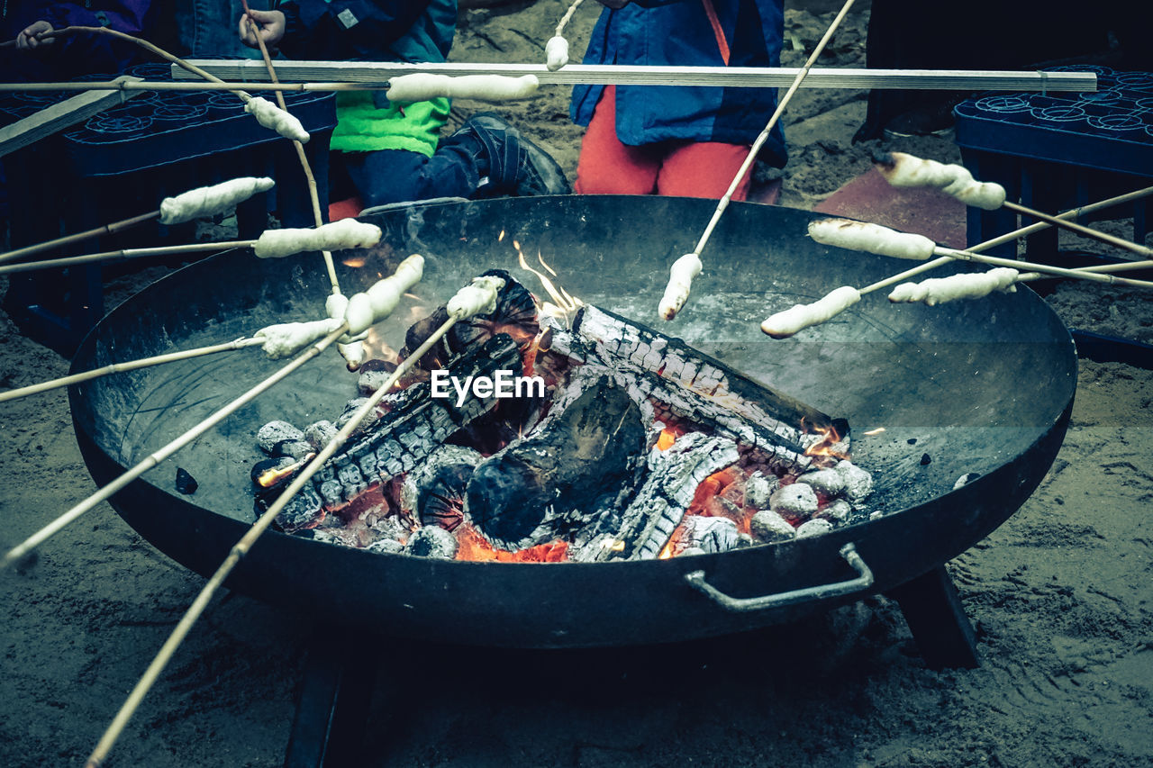 Midsection of people roasting marshmallows