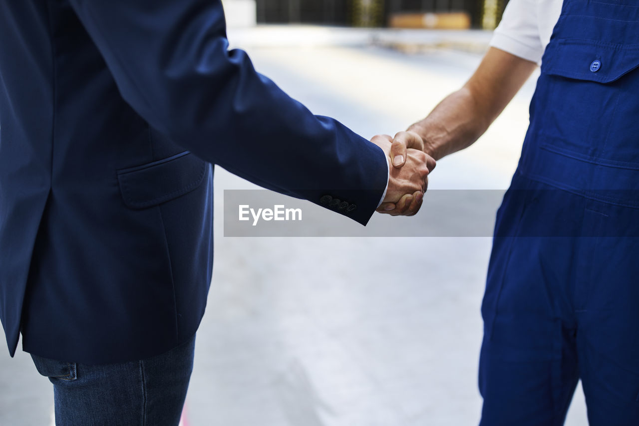 Close-up of businessman and worker shaking hands in a factory