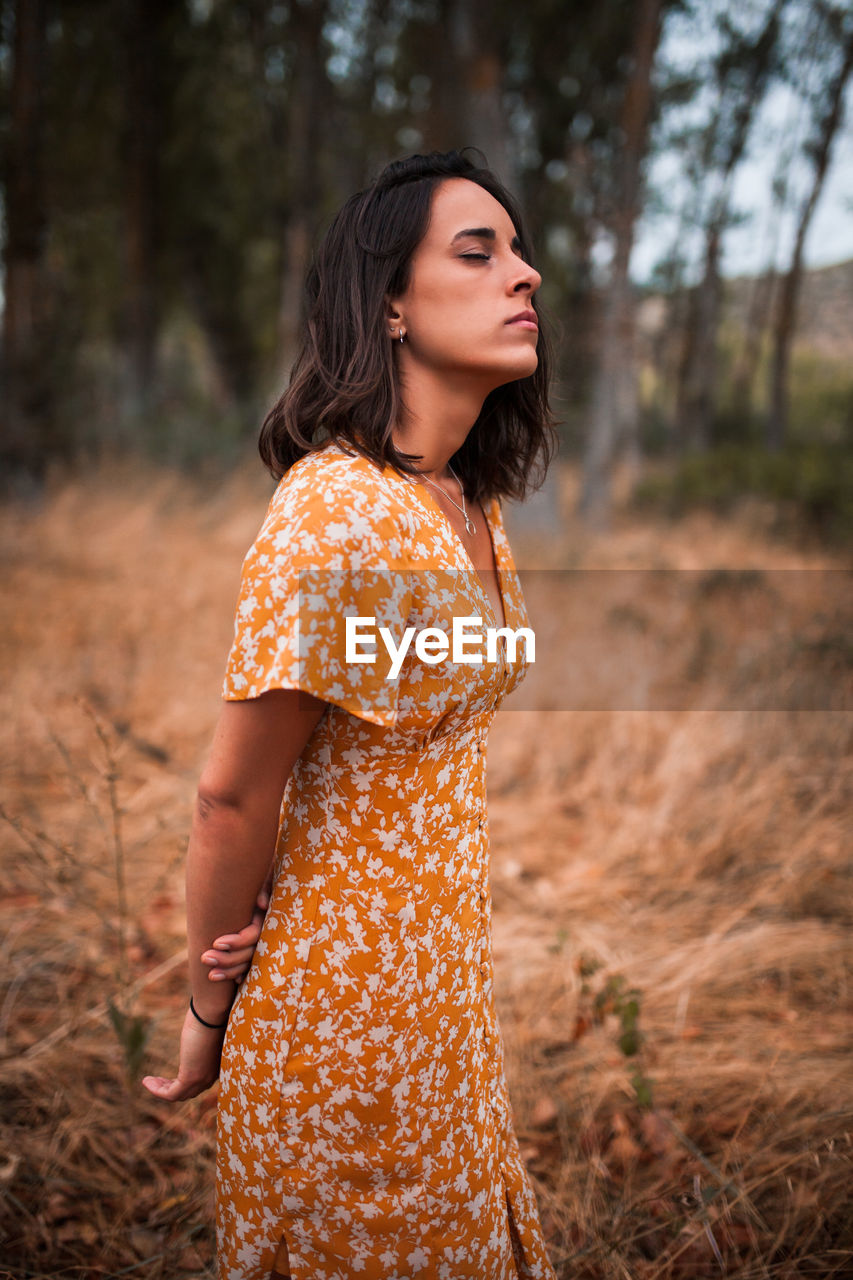 Beautiful young woman with closed eyes standing in forest