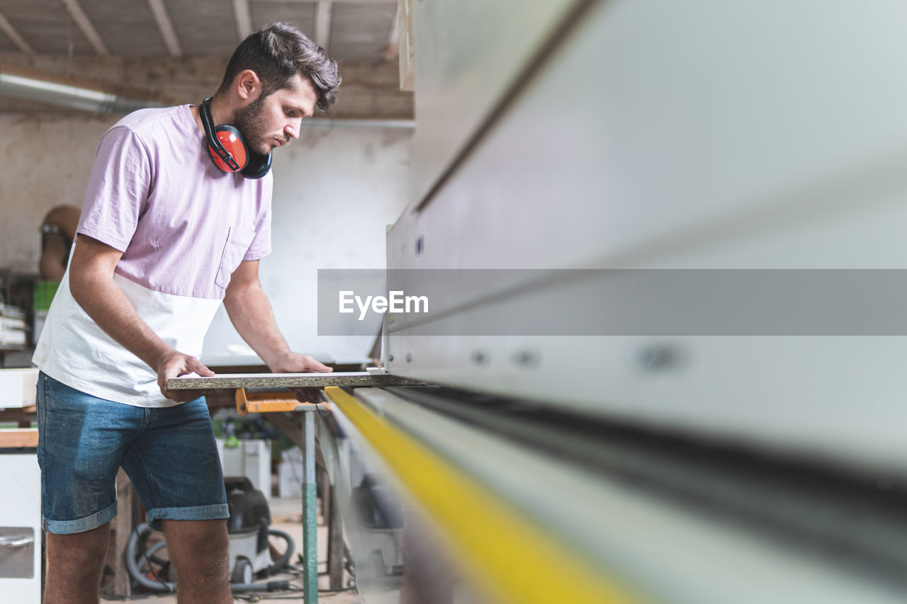 Male craftsperson holding plank while working in workshop