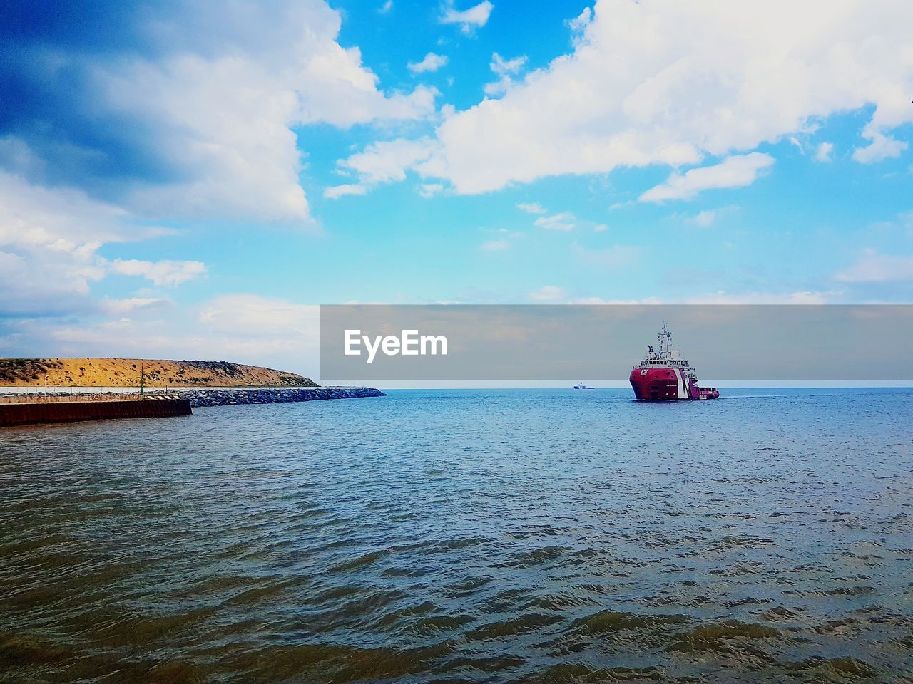 Boat sailing in sea against cloudy sky