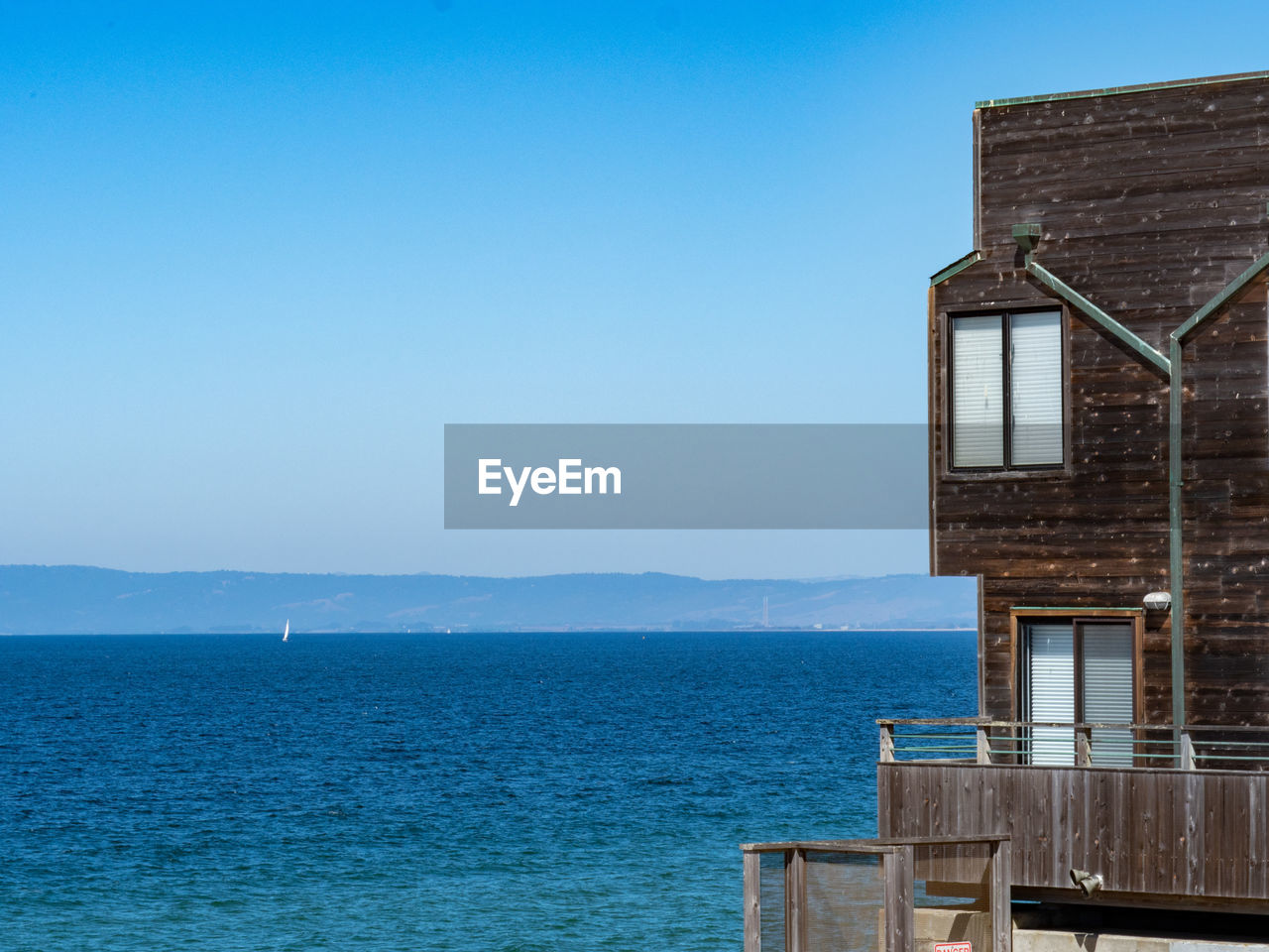 Building by sea against clear blue sky