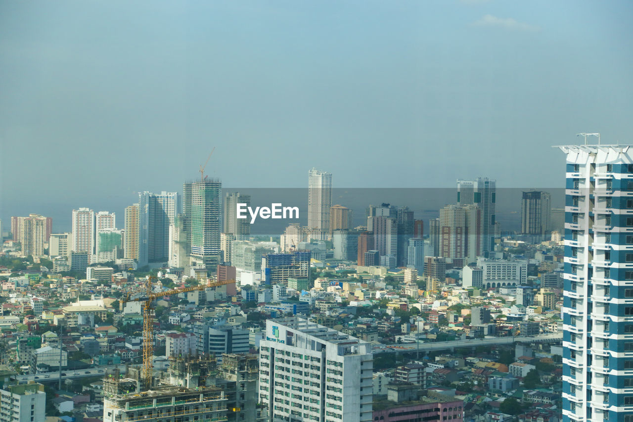 Aerial view of buildings in city against sky