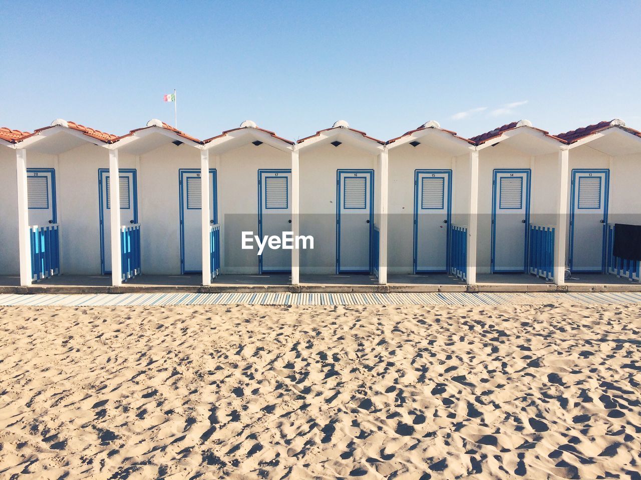 Huts at beach against sky on sunny day