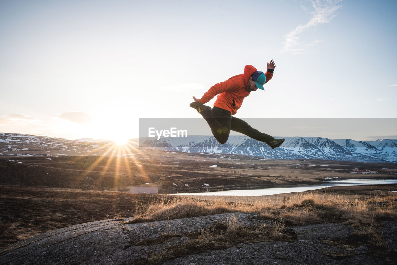 Man jumping with mountains and sun in background