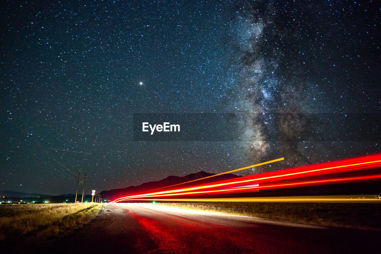 Light trails on road against sky at night