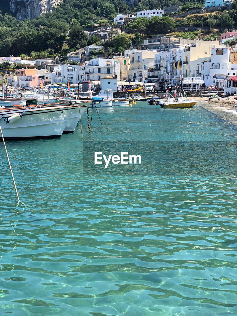 SAILBOATS MOORED IN SEA BY TOWN