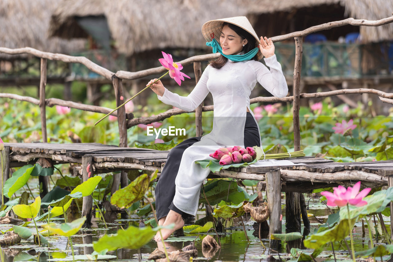 side view of young woman using mobile phone while sitting on field