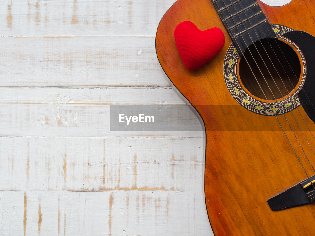 Directly above shot of guitar and heart shape on wooden table