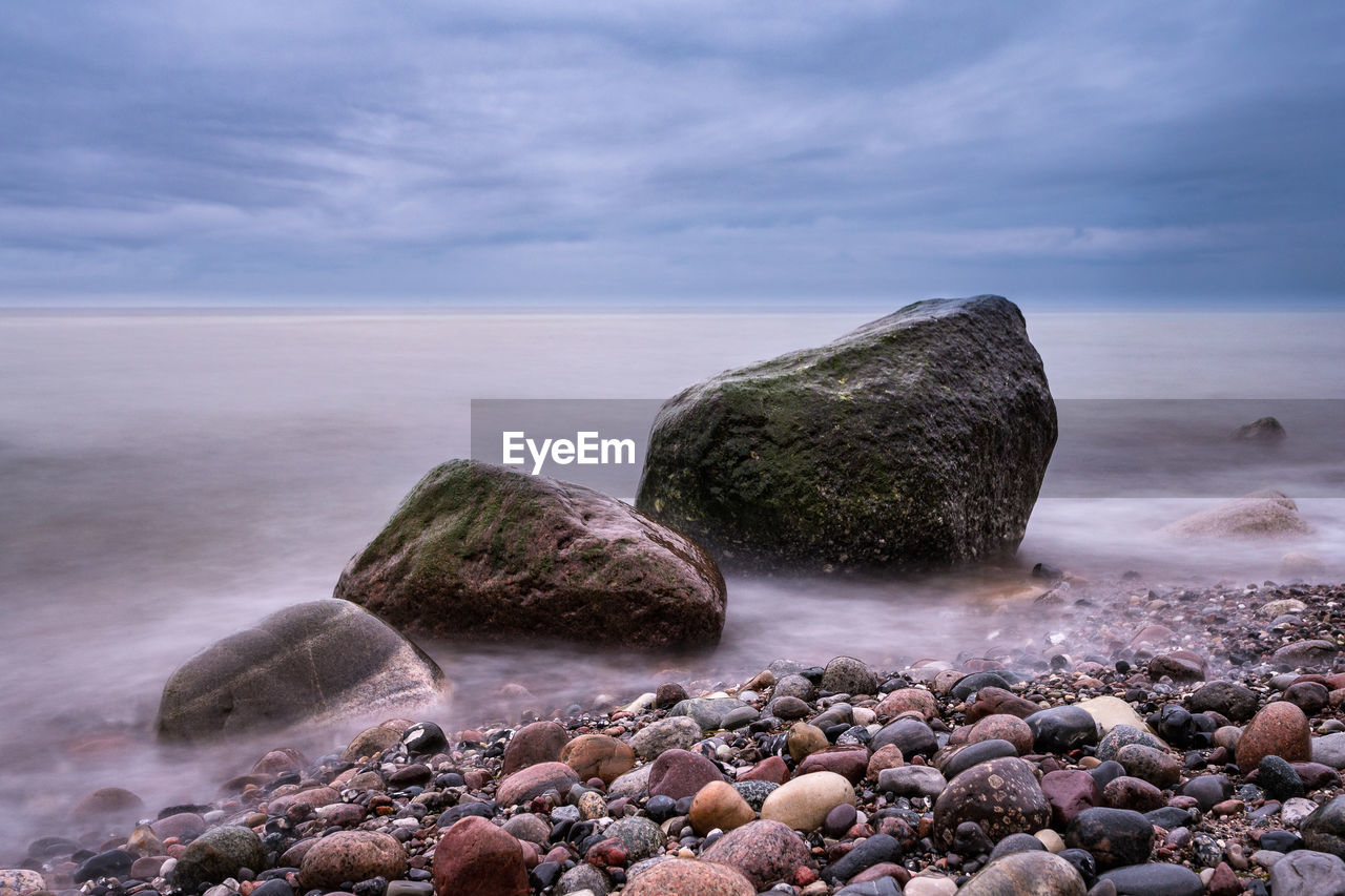 Scenic view of pebbles on beach against sky