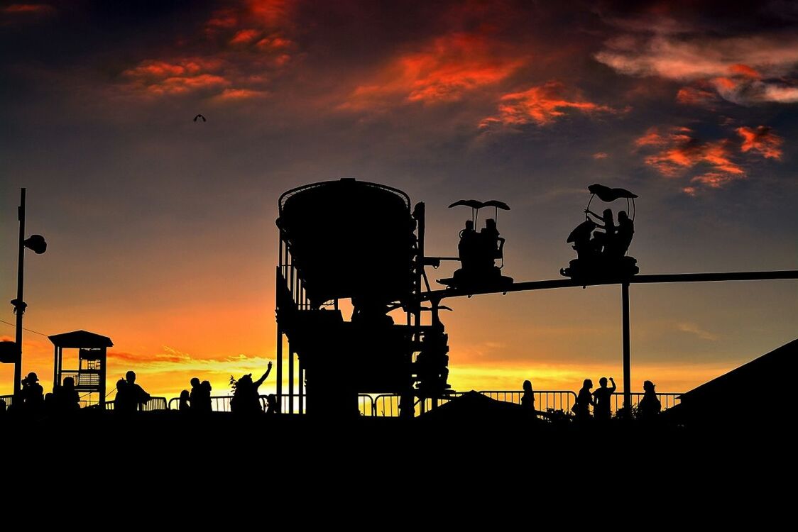 Silhouette people enjoying ride against the sky at sunset