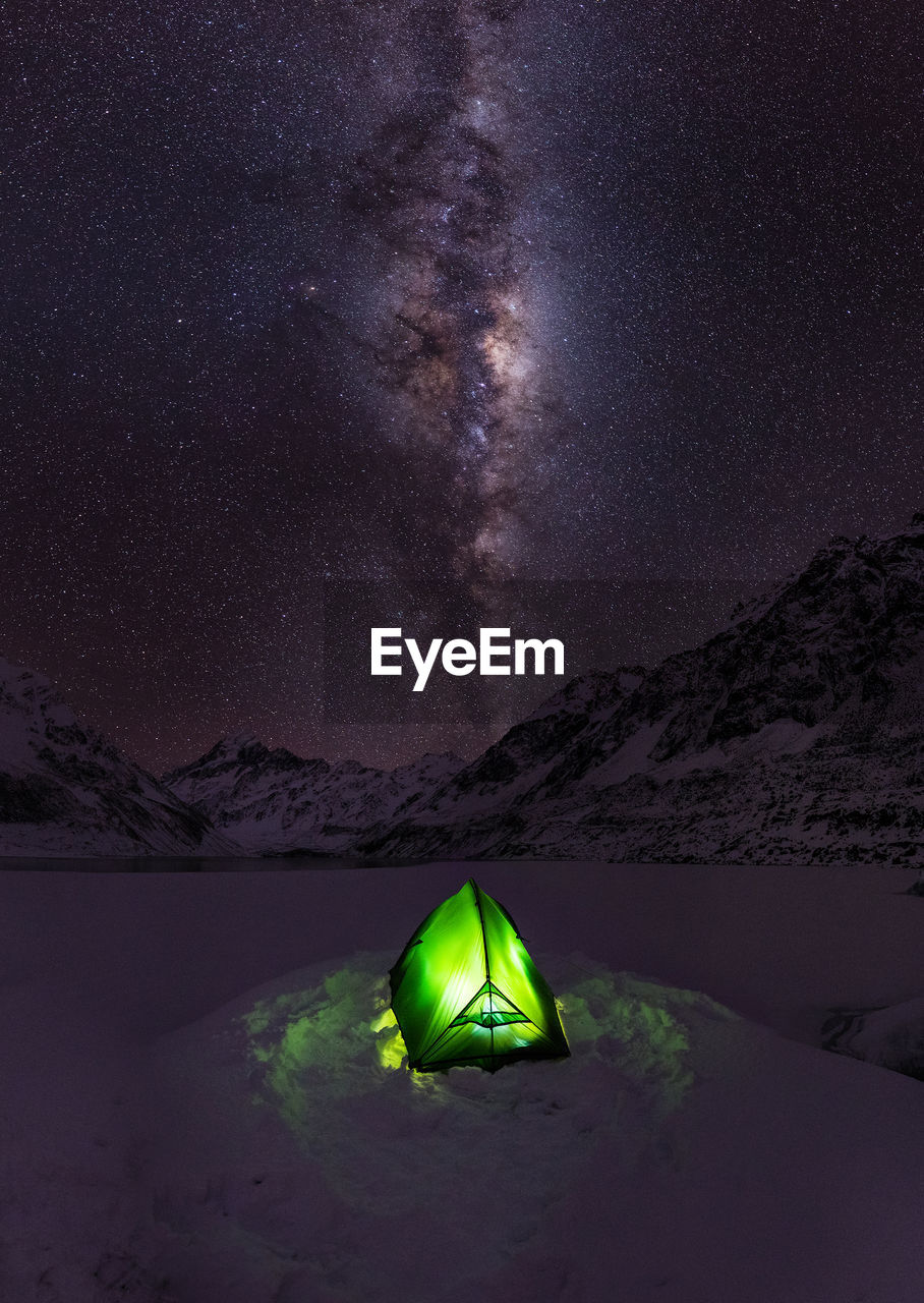 High angle view of illuminated tent on snow covered field against starry sky
