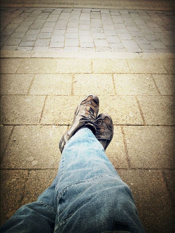 Low section of man sitting on sidewalk