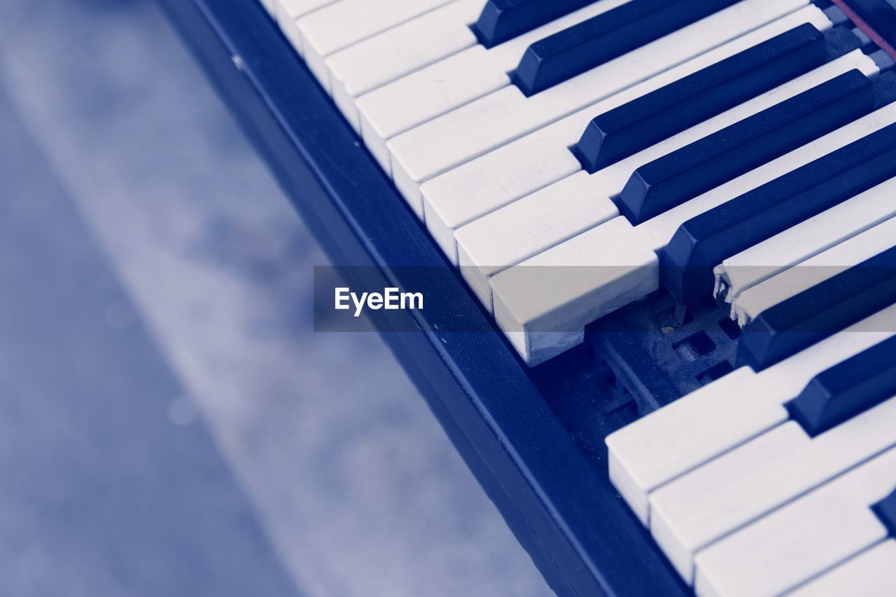 HIGH ANGLE VIEW OF PIANO KEYS IN BLUE SKY