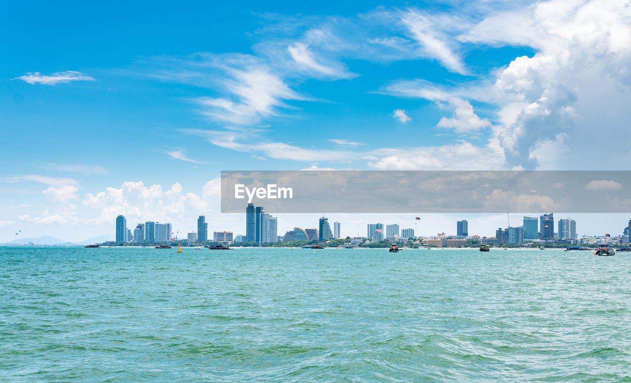 Sea and buildings in city against sky