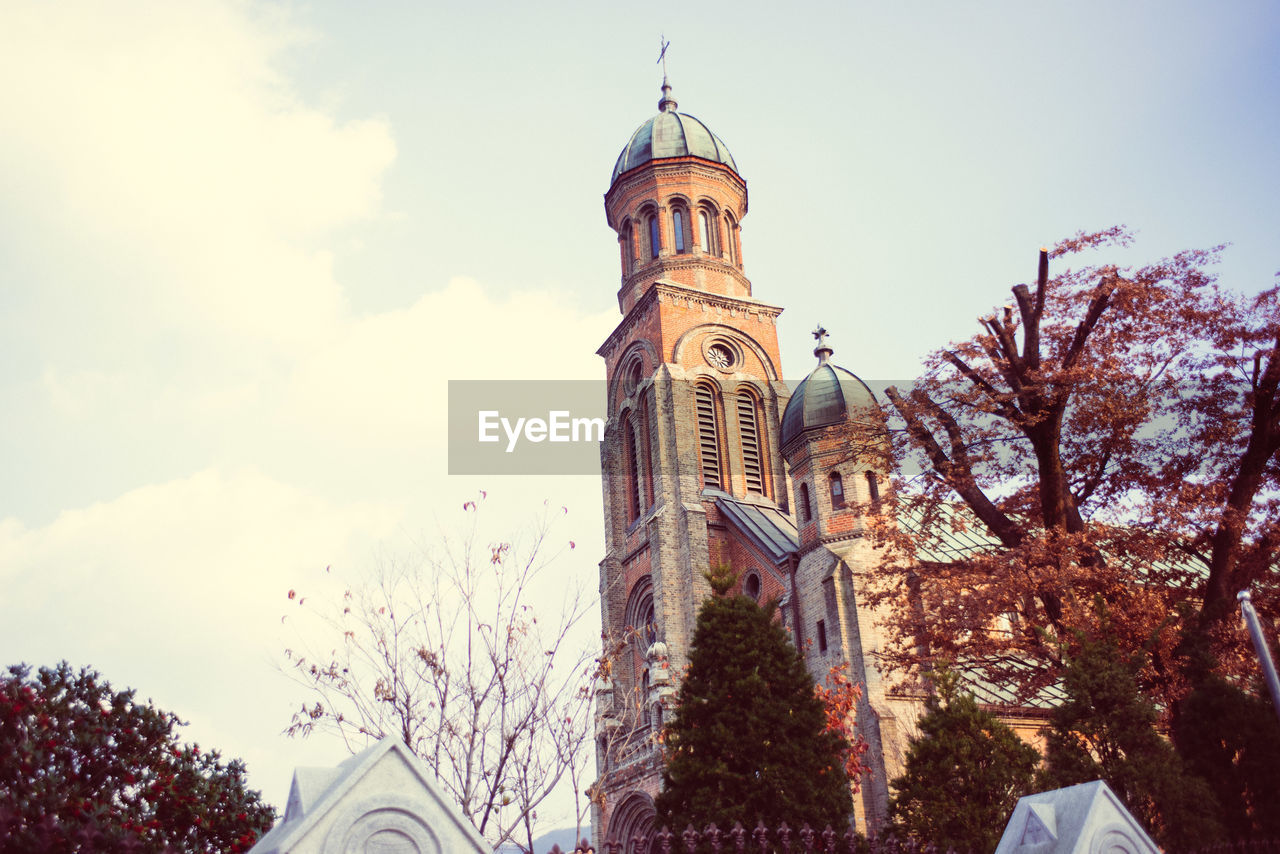 LOW ANGLE VIEW OF ILLUMINATED CLOCK TOWER AGAINST SKY IN CITY