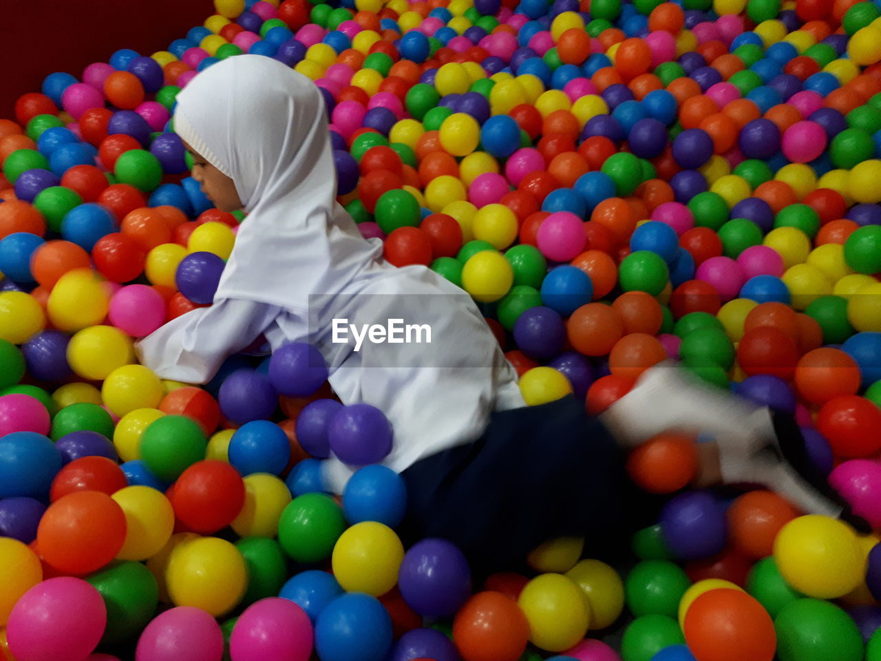 High angle view of girl playing on colorful balls