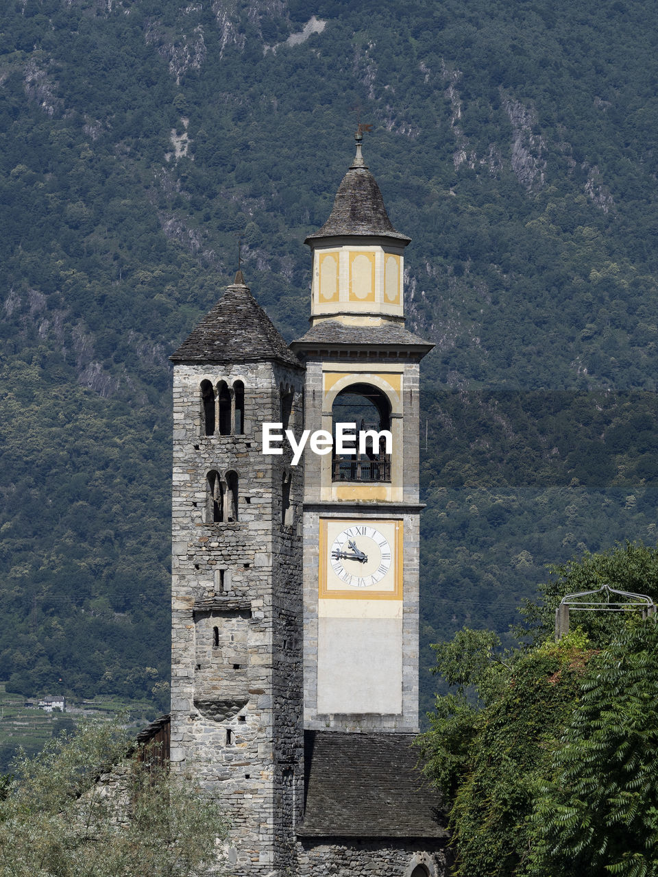 LOW ANGLE VIEW OF CLOCK TOWER AMIDST BUILDINGS