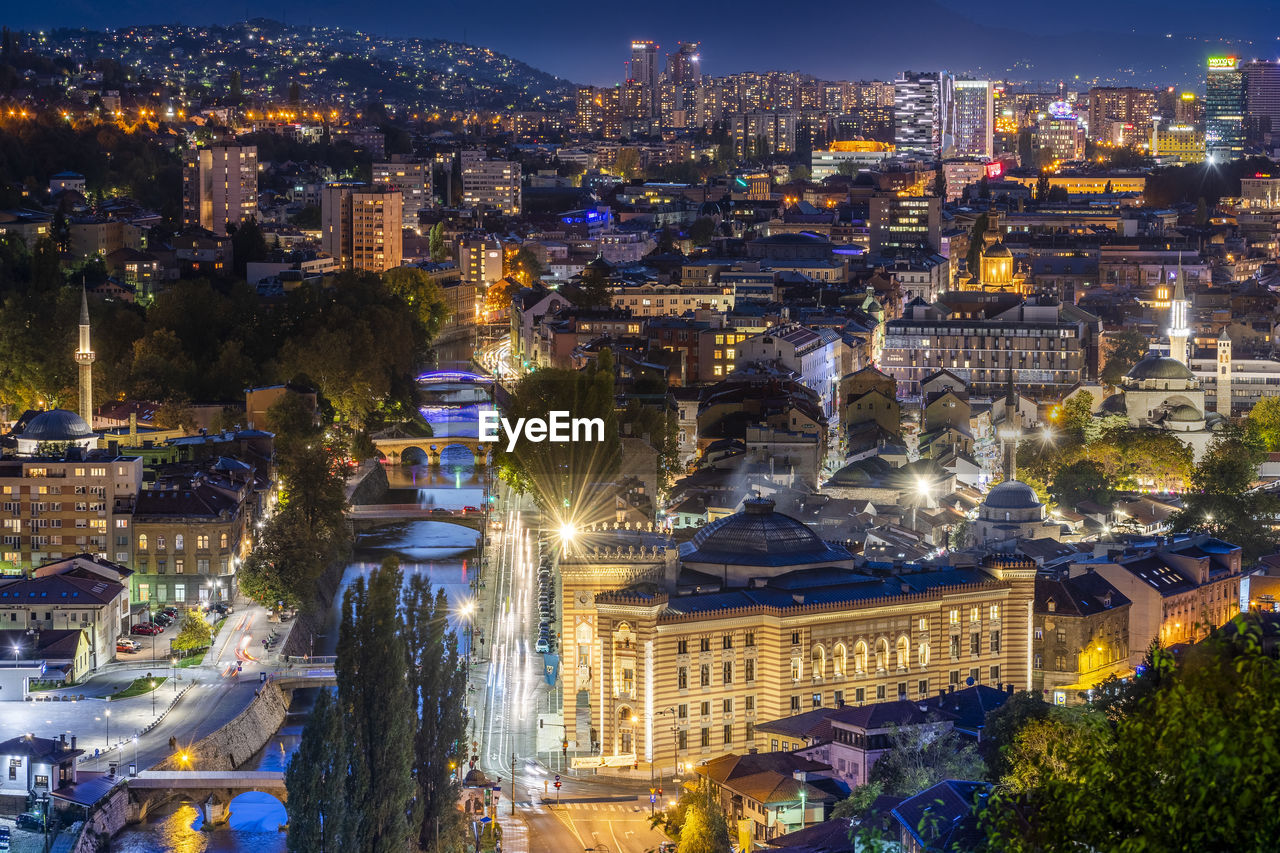 HIGH ANGLE VIEW OF ILLUMINATED BUILDINGS IN CITY