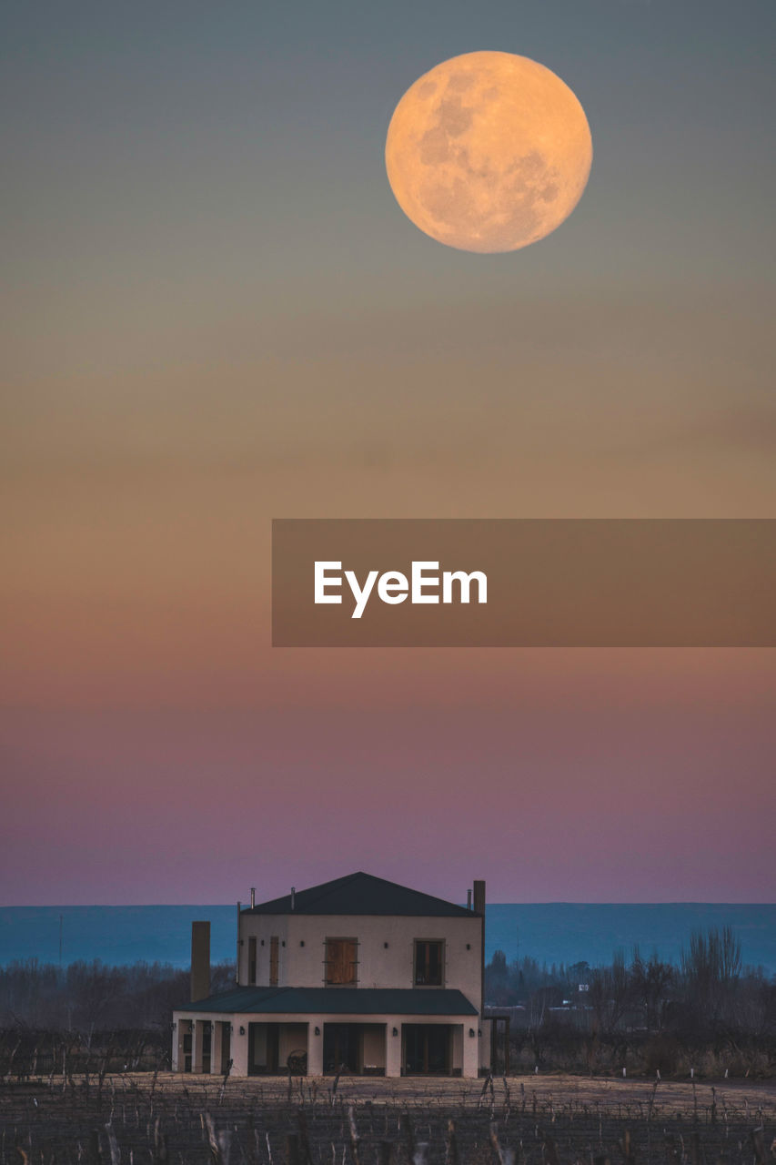 Full frame shot of building against sky during blue hour. full moon. 