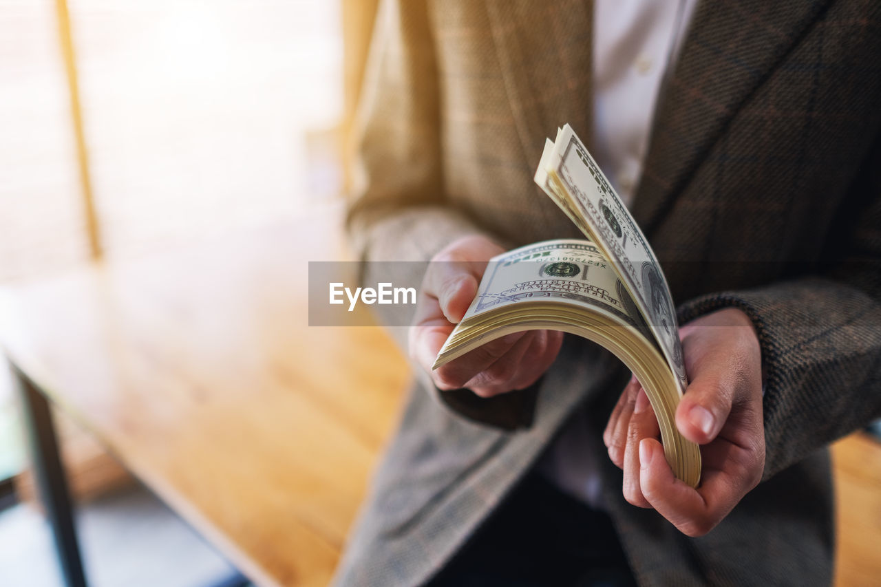 business, adult, one person, holding, men, finance, hand, formal wear, paper currency, currency, midsection, business finance and industry, indoors, businessman, clothing, person, close-up, wealth, focus on foreground, paper, occupation, corporate business