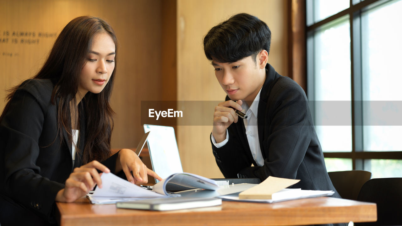 Young couple looking at camera while sitting on table