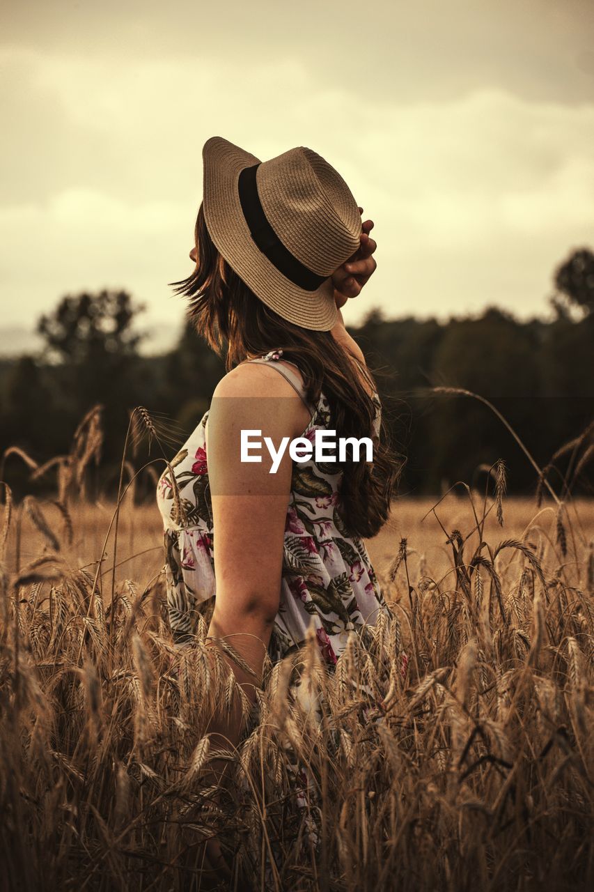 WOMAN WEARING HAT STANDING ON FIELD