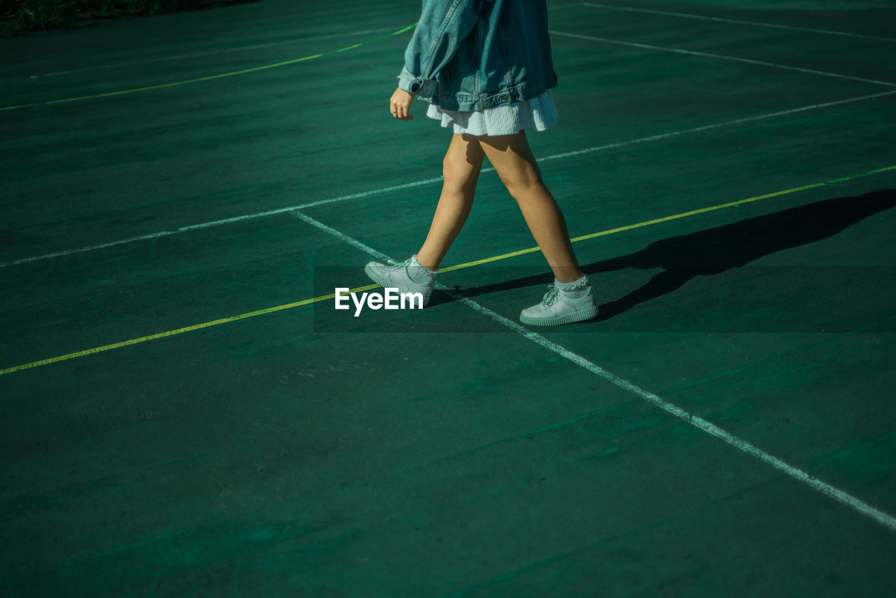 Low section of young woman walking in tennis court