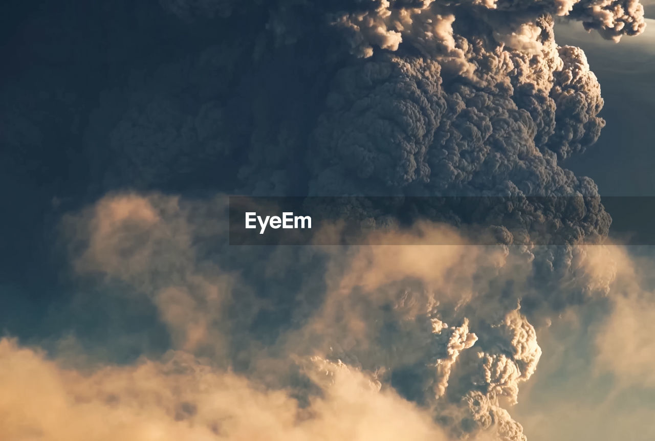 LOW ANGLE VIEW OF SMOKE EMITTING FROM VOLCANIC MOUNTAIN AGAINST SKY